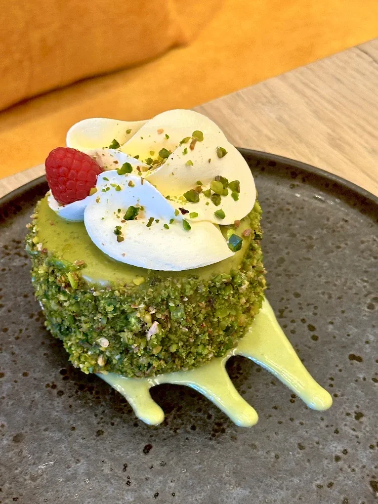 Pistachio dessert with cream and a raspberry